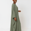 Beautiful woman wearing a stylish green modest dress with a matching headwrap, perfect for special occasions.