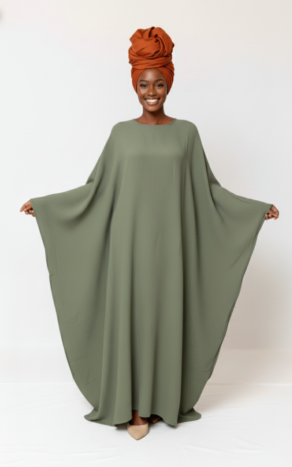 Beautiful woman wearing an olive green flowing dress paired with a stylish burnt orange headwrap.