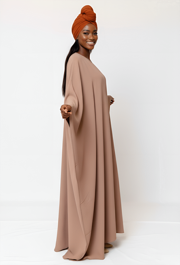 Beautiful woman in beige modest dress with orange headwrap, promoting stylish, conservative clothing.