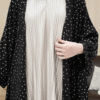 Close-up of modest fashion dress featuring pleated white fabric with a black polka dot outer layer, stylish and comfortable for women.