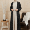 Stylish modest winter outfit featuring black polka dot coat and cream pleated dress for women.