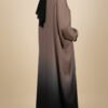 Woman wearing a stylish gradient abaya with black hijab, full-length modest fashion.