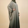 Woman wearing a stylish, modest abaya with embroidery and a green hijab.