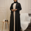 Beautiful woman wearing stylish modest black abaya and hijab, indoor setting.