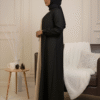 Stylish woman wearing black and beige abaya with hijab, elegant decor for modest fashion showcase.