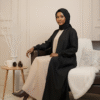Beautiful woman wearing stylish modest black and beige outfit with hijab, cozy winter decor.