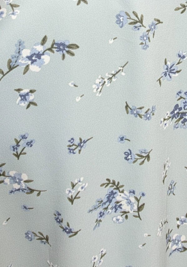 Light blue floral fabric with small white and blue flowers and green leaves.