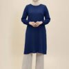Woman wearing a stylish navy blue modest dress with beige wide-leg pants and black boots.