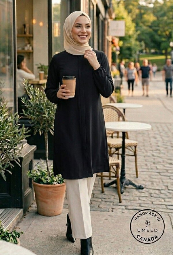 Elegant woman in modest black dress and beige hijab holding coffee outside a cafe.
