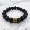 Black lava stone bracelet with gold accent bead, handmade jewelry.