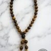 Beaded wooden necklace with gold accents on marble background.