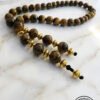 Beaded wooden prayer beads with gold accents on a marble surface.