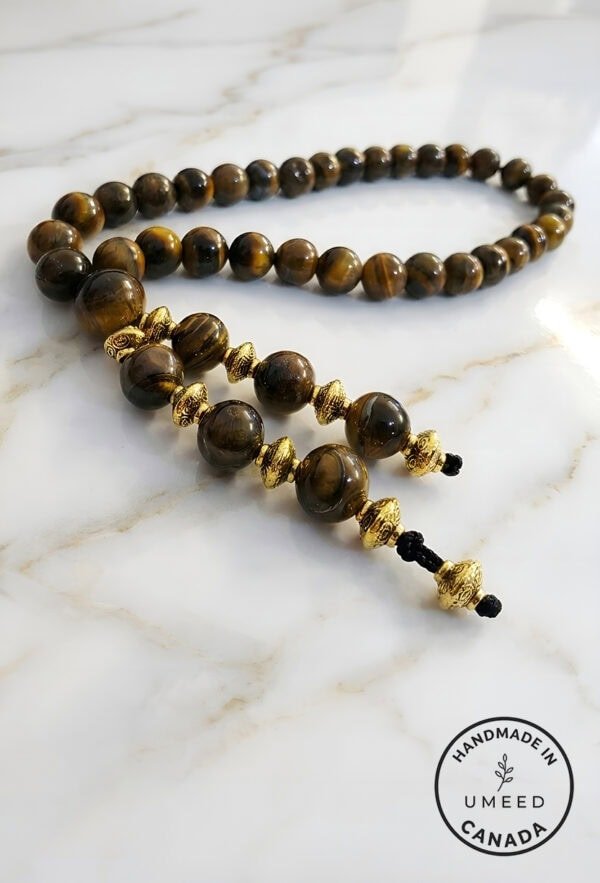 Beaded wooden prayer beads with gold accents on a marble surface.