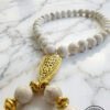 Elegant white and gold beaded necklace with intricate pendant design.