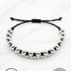 Handmade beaded bracelet with black and silver beads on a white marble background.