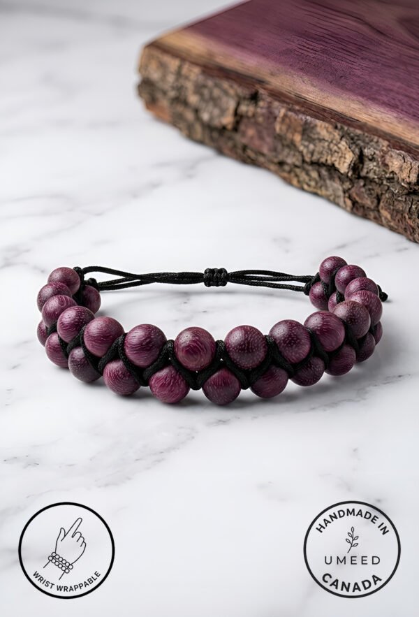 Handmade purple beaded bracelet with adjustable cord on marble surface.