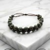 Handmade beaded bracelet with adjustable cord on marble surface.