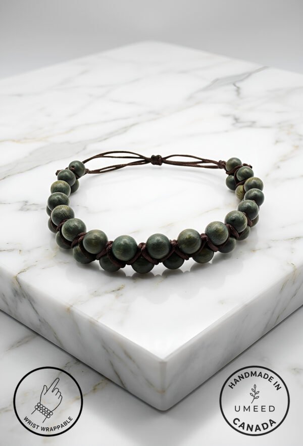 Handmade beaded bracelet with adjustable cord on marble surface.