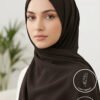 Elegant woman wearing a black hijab with light makeup and natural background.