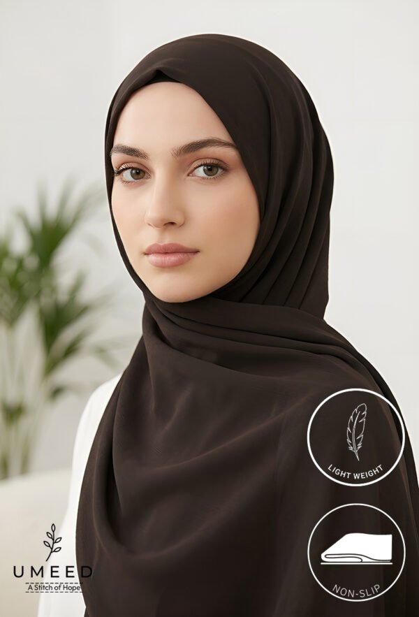 Elegant woman wearing a black hijab with light makeup and natural background.