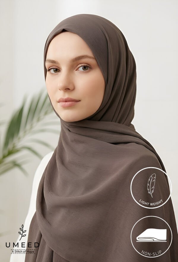 Elegant woman wearing a taupe hijab with a light background and green plant.