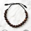 Handmade wooden bead bracelet with adjustable cord on marble background.