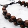 Handmade wooden beaded necklace with adjustable cord on white marble background.