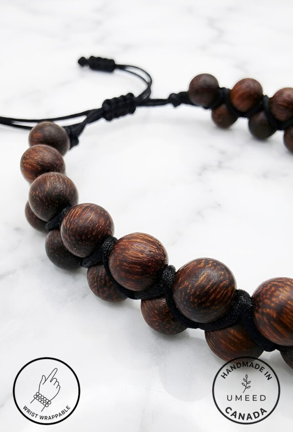 Handmade wooden beaded necklace with adjustable cord on white marble background.