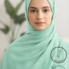 Elegant woman wearing light green hijab with natural background.