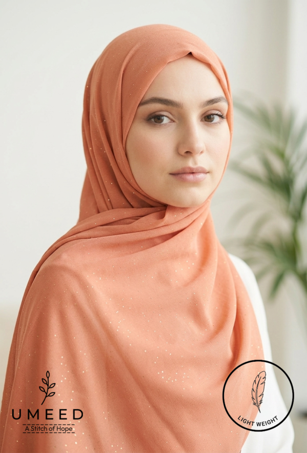 Beautiful young woman wearing a peach hijab with subtle sparkle details.