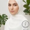 Elegant woman wearing a white hijab with green plant background.